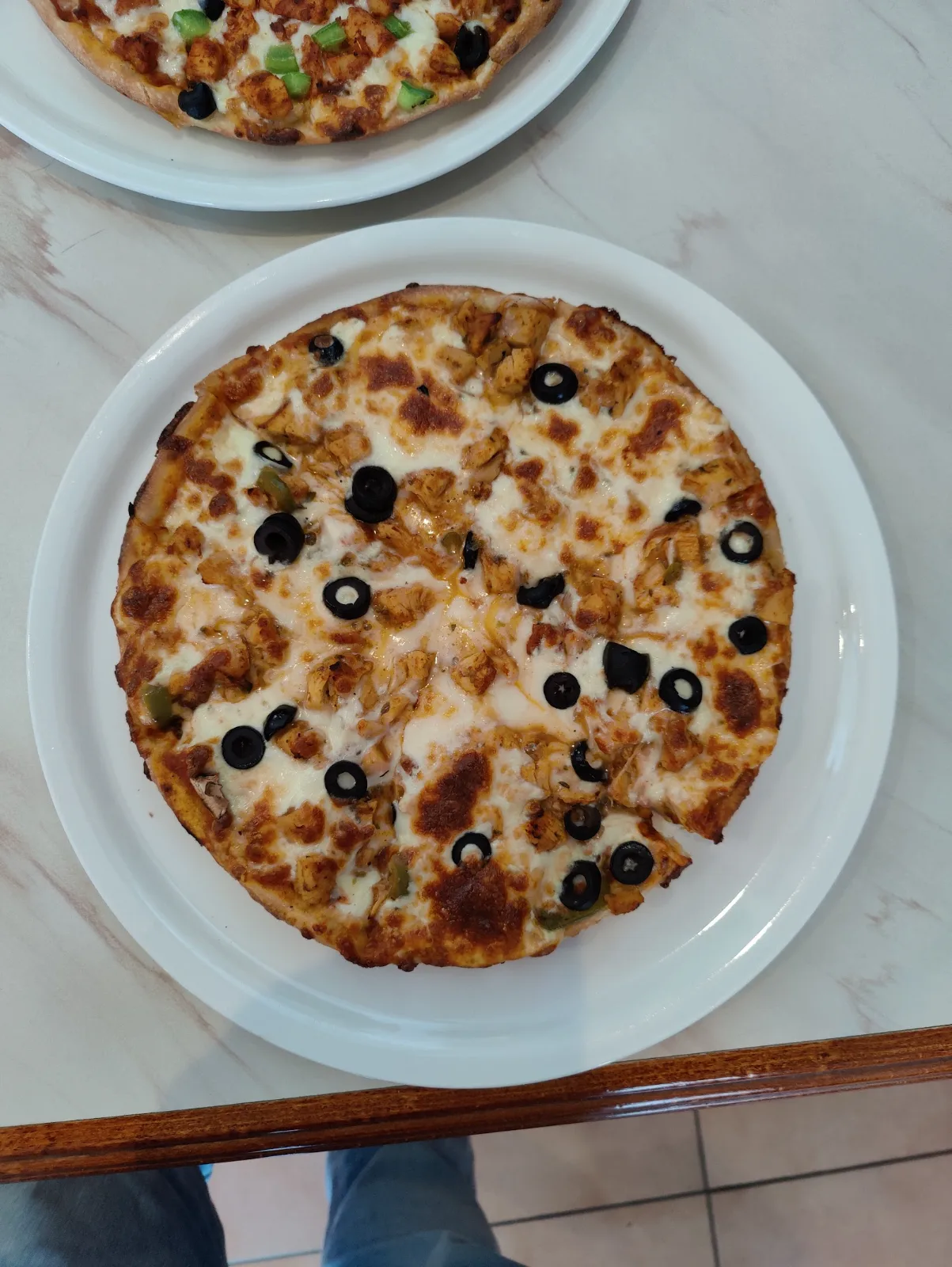 Pizza med ost och svarta oliver på vit tallrik